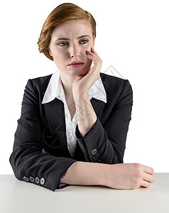 思考坐在办公桌前的红头发女商务人士图片