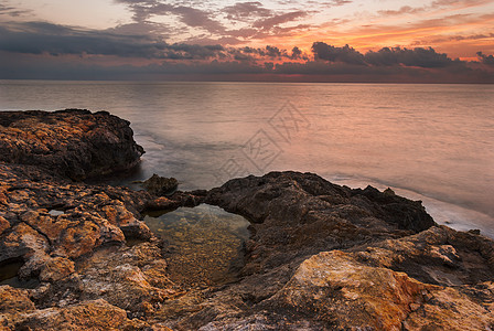 日落时落的洛基海滩反射水池风景岩石橙子日落海洋场景旅行石头图片
