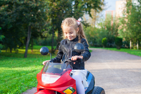 穿着皮夹克的小女孩 坐在玩具摩托车上图片