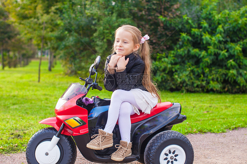 穿着皮夹克的可爱小女孩 坐在玩具摩托车上图片