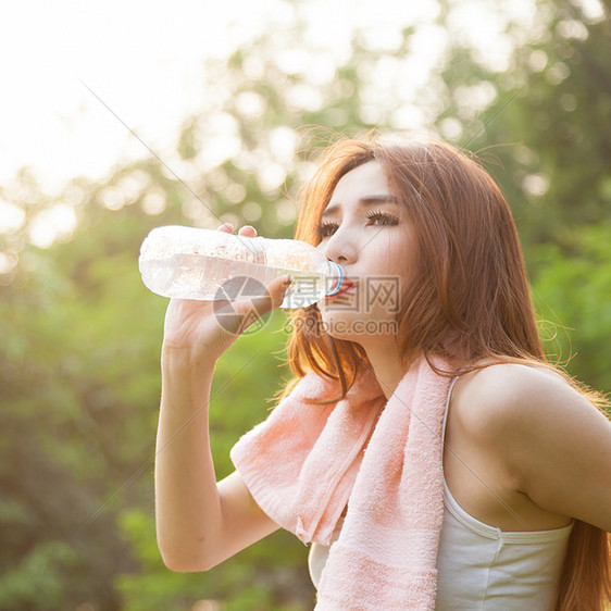 妇女在锻炼后坐着疲劳和饮用水毛巾日落公园运动瓶子成人身体阳光女士女性图片