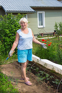 年长妇女站在花园中间的花园里图片
