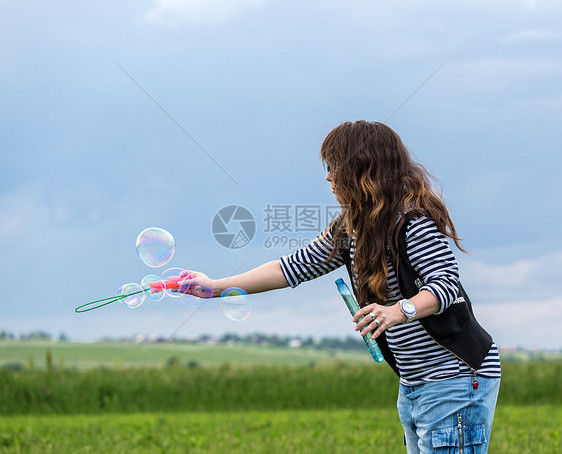 美丽的年轻女子做吹泡泡泡日光幸福场地阳光女性晴天女士气泡草地乐趣图片