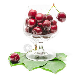 绿色新鲜叶子上清红酒杯中的樱桃莓果水果图片