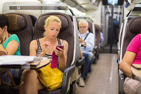 女士乘火车乘坐智能手机旅行商业电话民众时间表乘客女孩工作时间互联网上网图片