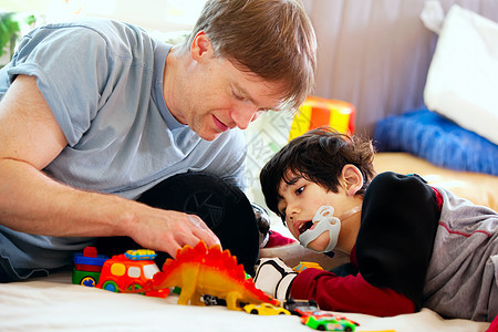 和残疾儿子玩汽车的英俊父亲脑瘫男人游戏保姆混血玩具需求微笑家庭地面图片