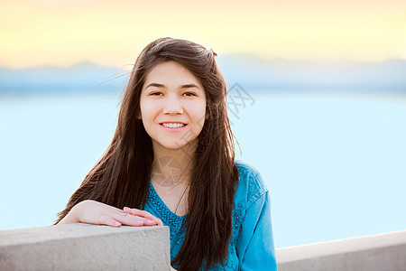 美丽的少女女孩在日落时 享受户外的湖边蓝色青少年海洋微笑地平线孩子混血混血儿女性图片