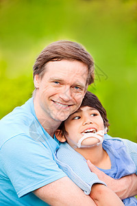 英俊父亲 在户外带着微笑的残疾儿子照顾者保姆混血儿需求脑瘫孩子蓝色乐趣男生混血图片