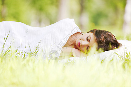 睡在草地上的女人自由场地女孩睡眠白色绿色枕头公园毯子黑发图片