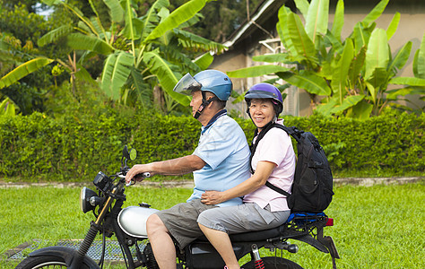 驾驶摩托车旅行的亚裔老年夫妇乘摩托车旅行头盔闲暇公园男人祖父享受女性退休娱乐家庭图片