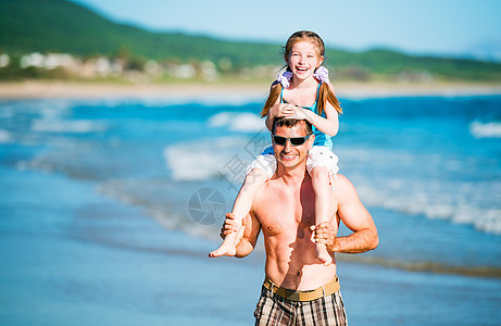 父亲和女儿在海滩上海岸成人阳光天空喜悦假期微笑活动男性爸爸图片