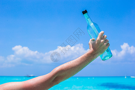 手背景蓝色天空中含有信息插件的瓶支撑旅游抛弃海滩救援气泡热带文档旅行帮助图片