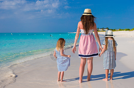 母亲和小女儿背对背视 享受暑假乐趣女孩女士异国晴天帽子家庭婴儿幸福海岸线图片