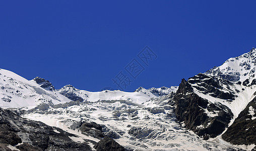 雪下和清蓝天空下的高加索山脉爬坡岩石荒野季节天蓝色天空旅游旅行冻结蓝色图片