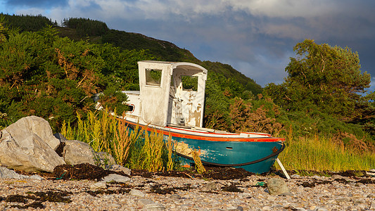 小船在石滩湖边的小沉船海滩船运土地腐烂海岸太阳石头港口日落木板图片