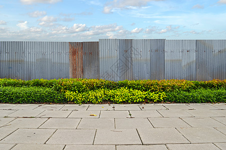蓝天背景下有锌栅栏的灌木红色树篱叶子瓦楞衬套建筑学天空金属工业绿色图片