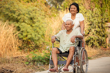 高级妇女将残疾丈夫推上轮椅的年长妇女男人家庭保健人士夫妻医疗帮助男性公园老年图片