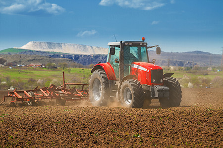 田地上新的红色拖拉机在陆上工作食物机器土壤地球灰尘收获土地生长农场商业图片