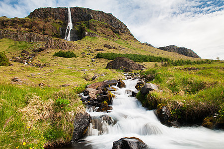 冰岛的瀑布丘陵石头天空流动旅行力量山脉岩石绿色巨石图片