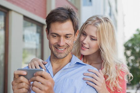 看着智能手机的时尚年轻夫妇感情闲暇都市男性成人夫妻活动拨号电话技术图片