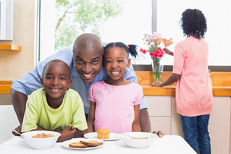 家人早上一起吃早饭快乐的一家人儿子桌子花朵早餐服装家庭生活男人混血女孩勺子图片