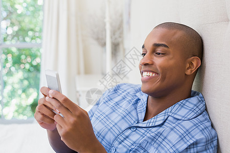 欢乐男人坐在床上和手机发短信闲暇短信沟通拨号羽绒被公寓住所家庭卧室睡衣图片