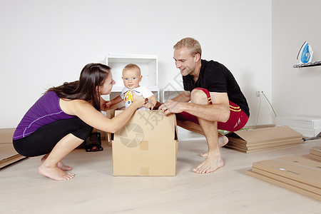 带婴儿运动的年轻家庭家具女朋友男人赤脚地面女士开箱纸板工具微笑图片