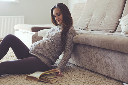 怀孕妇女的家庭肖像羊毛女孩地毯父母腹部房间女性沙发母性肚子图片