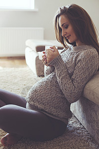 怀孕妇女的家庭肖像母亲腹部母性父母羊绒女性杯子咖啡沙发情绪图片