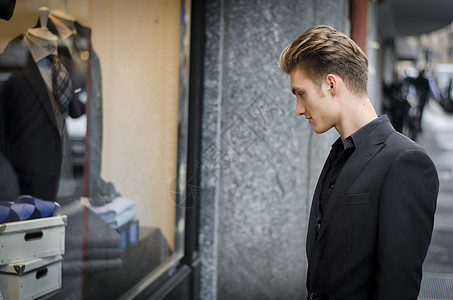 年轻男子在商店窗口看时装物品购物套装精品男士男性黑色项目杂志夹克窗户图片
