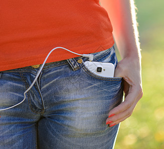在  妇女袖珍袋  中带耳机的智能手机营销音乐手指白色互联网电脑头巾网络口袋电话图片