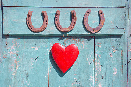 3个老旧的生锈马蹄铁幸运符号和门上的红心图片