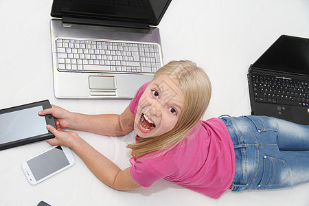 在家里用平板 笔记本电脑和电话玩游戏的小孩教育女孩们互联网药片童年沙发快乐幸福儿童孩子图片