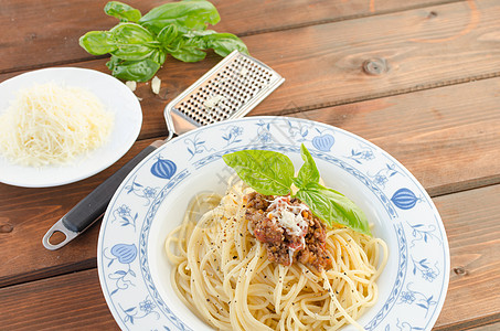 木制桌上的意大利面条 Bolognese猪肉勺子餐厅午餐蔬菜厨房食谱烹饪食物叶子图片