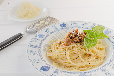 木制桌上的意大利面条 Bolognese香料餐巾勺子猪肉叶子蔬菜盘子烹饪美食厨房图片