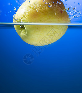 喷水时的黄苹果液体运动行动气泡反射飞溅水果蓝色黄色海浪图片