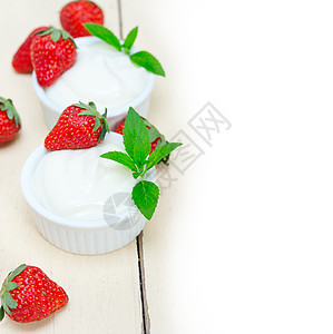 奶油草莓希腊有机酸奶和草莓叶子木头薄荷旋转勺子奶油乳制品乡村奶制品牛奶背景
