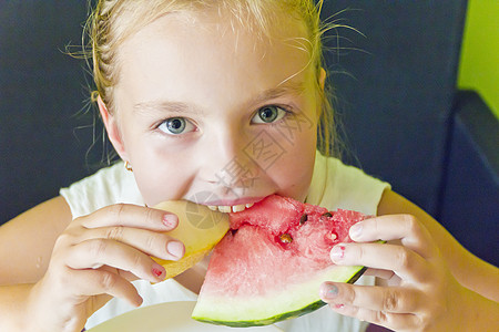 可爱的女孩吃西瓜和甜瓜白色蓝色孩子女学生金发童年图片