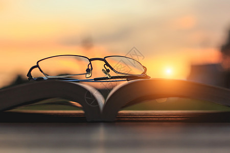 日落时把眼镜和书放在桌上桌子学习知识字典大学故事智慧教育教科书商业背景图片