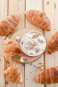 新鲜羊角面包和咖啡泡沫针织咖啡杯焙烤食品时光早餐奶油糕点食物背景图片