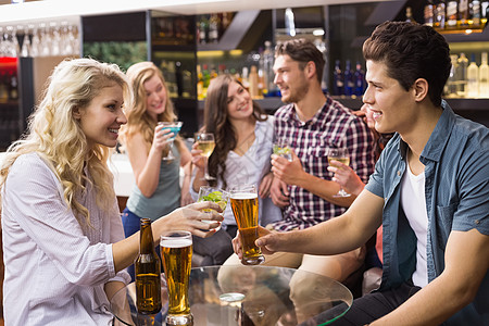 年轻朋友一起喝酒的年青朋友酒吧女士快乐讨论男人女性休闲友谊啤酒微笑图片