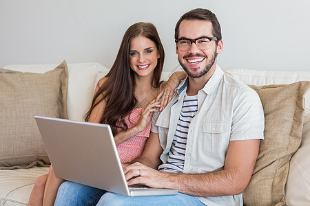 在沙发上使用膝上型电脑的短裙夫妇技术快乐微笑住所家庭房子女士男性闲暇女朋友图片
