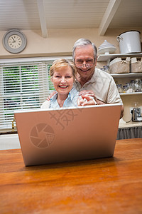 使用笔记本电脑一起使用的老年夫妇女性男人台面快乐闲暇家庭男性技术微笑桌子图片