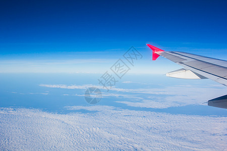 机翼飞机在云上飞翔 从西向天空仰望引擎技术红色航班白色空气窗户旅行喷射商业图片