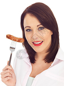 在叉子上持有猪香肠的年轻女子食物女士女性猪肉油炸成人白色黑发香肠冒充图片