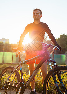 在日出时骑着山上自行车骑自行车的运动员 健康生活方式爬坡娱乐乐趣下坡成人男人山地车耀斑男性太阳图片