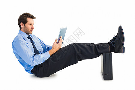 坐在公事包上用脚踏着平板板板的商务人士衬衫男性棕色短发蓝色专注领带公司人士地面图片