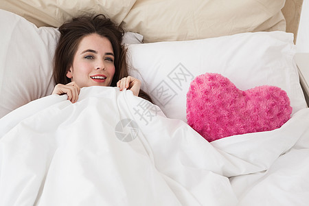漂亮的黑发美女睡在有心垫的床上图片