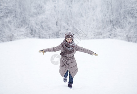 快乐的小女孩跑在雪上蒙着圆珠彩的背景下小姑娘女孩情感针织雪堆童年女性公园夹克帽子图片