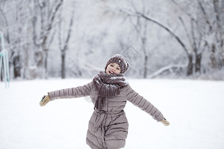 快乐的小女孩跑在雪上蒙着圆珠彩的背景下季节情感女性帽子针织夹克衣服雪堆孩子冬装图片